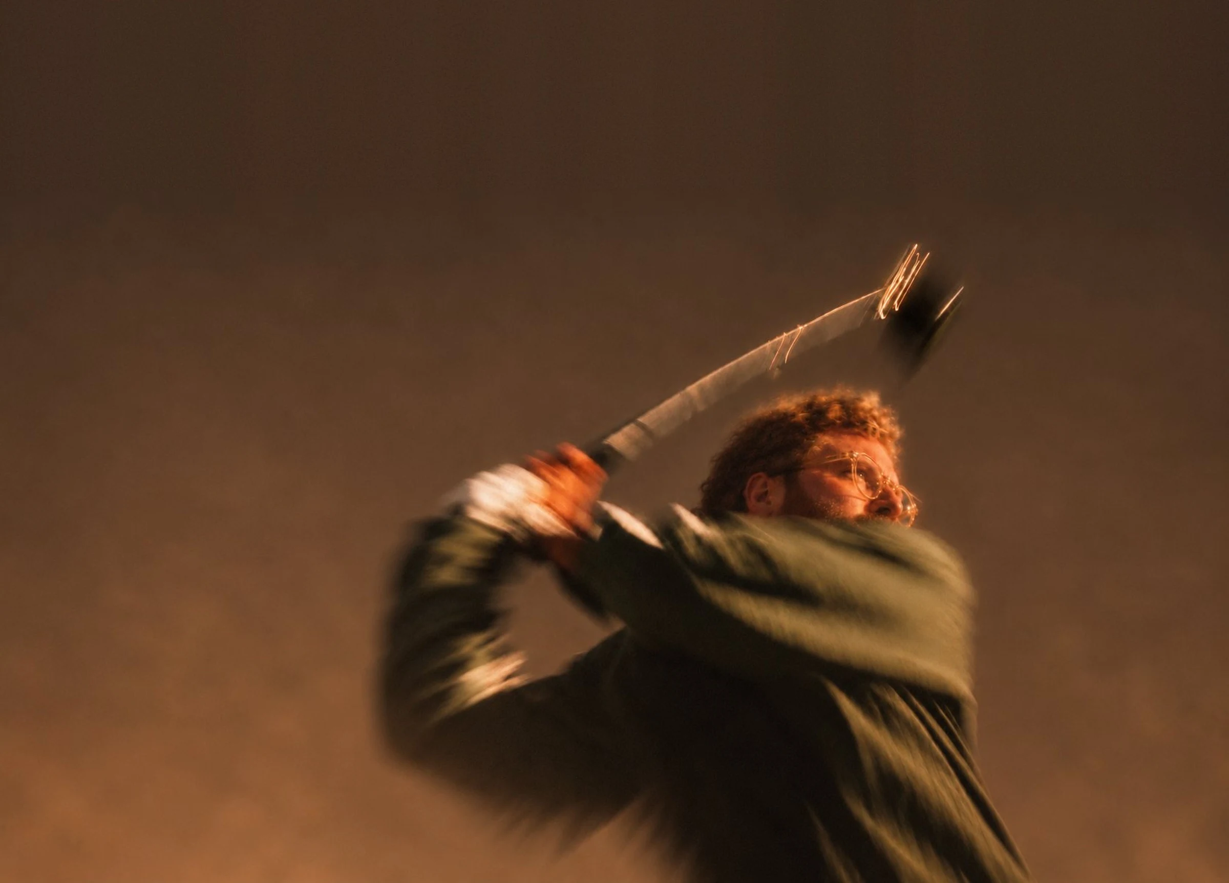 Golfer mit Brille mitten im Schwung, warmes Licht, Bewegungsunschärfe.