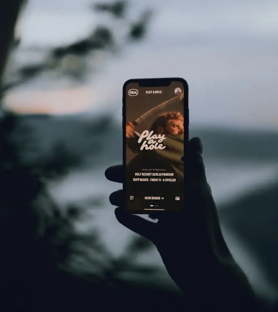 Hand hält ein iPhone mit der Pah! App in der Dämmerung.